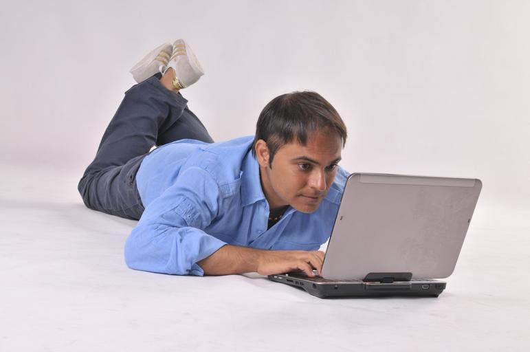 Chlap v modrej košeli pracuje s notebookom