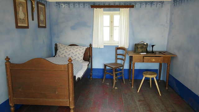 Starožitná drevená posteľ v izbe s oknom